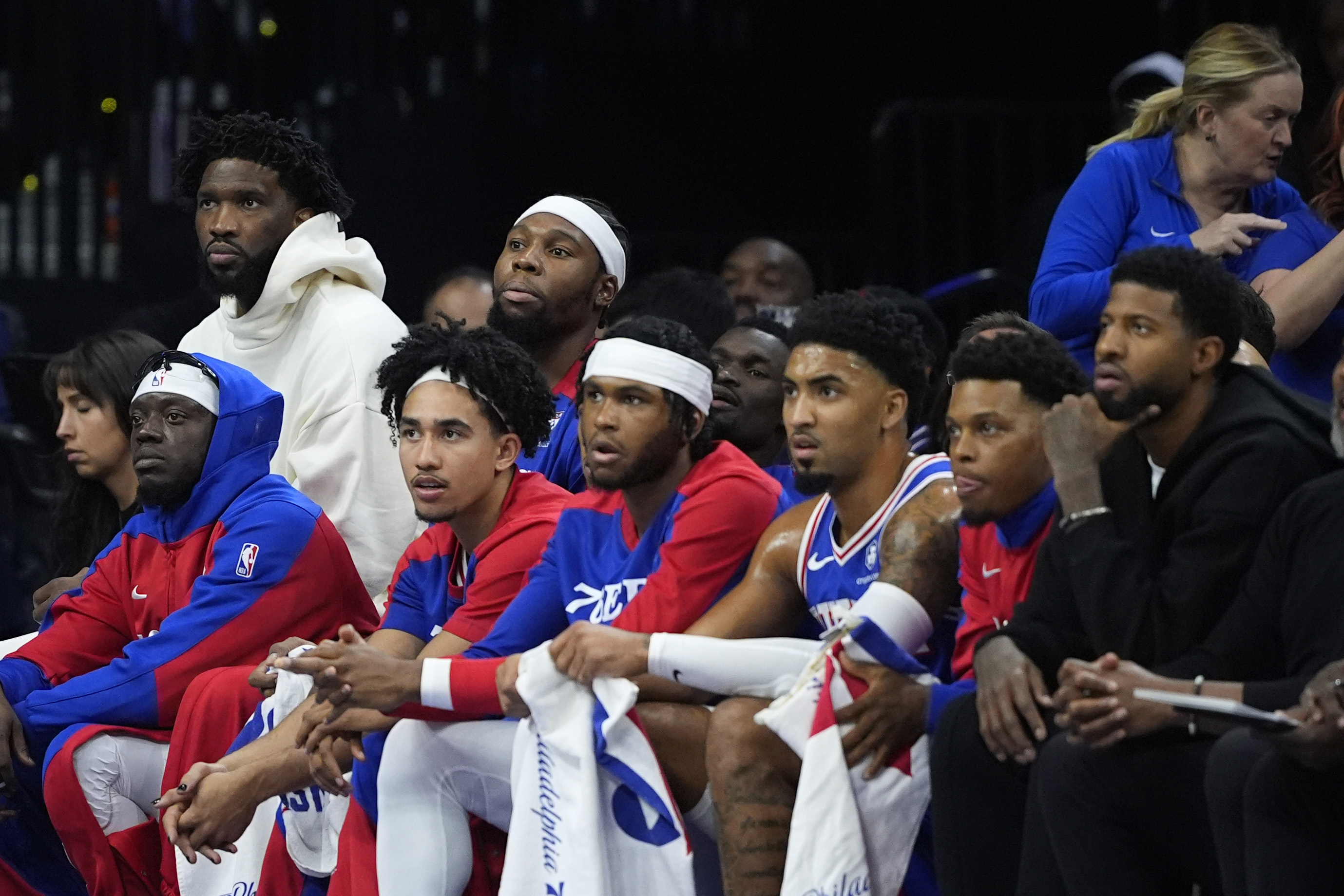 Philadelphia 76ers' Joel Embiid, top left, and Paul George, bottom right, watch from the bench during the first half.