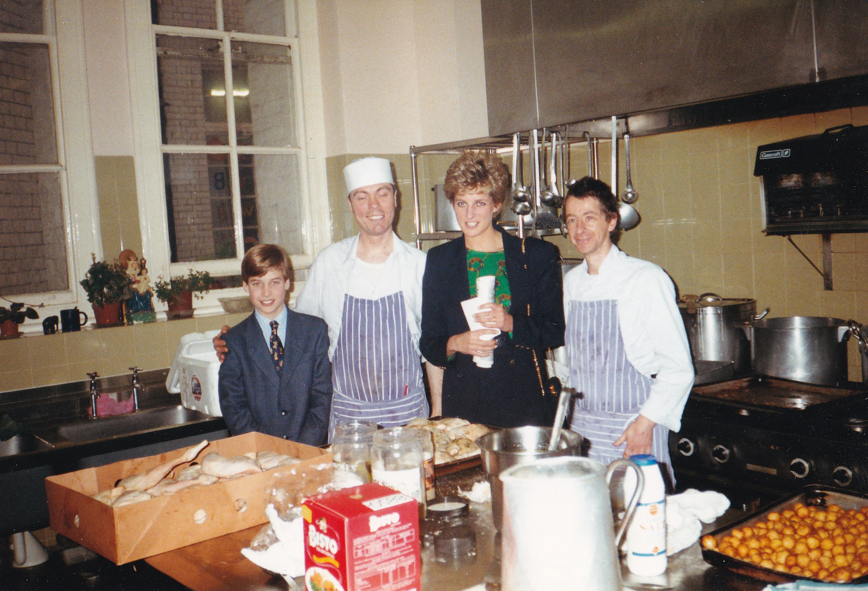 Princess Diana (2R) with her 11-year-old son William (L), now Prince of Wales in the kitchens during one of his first visits to homelessness charity, The Passage in London, taken on December 14, 1993.