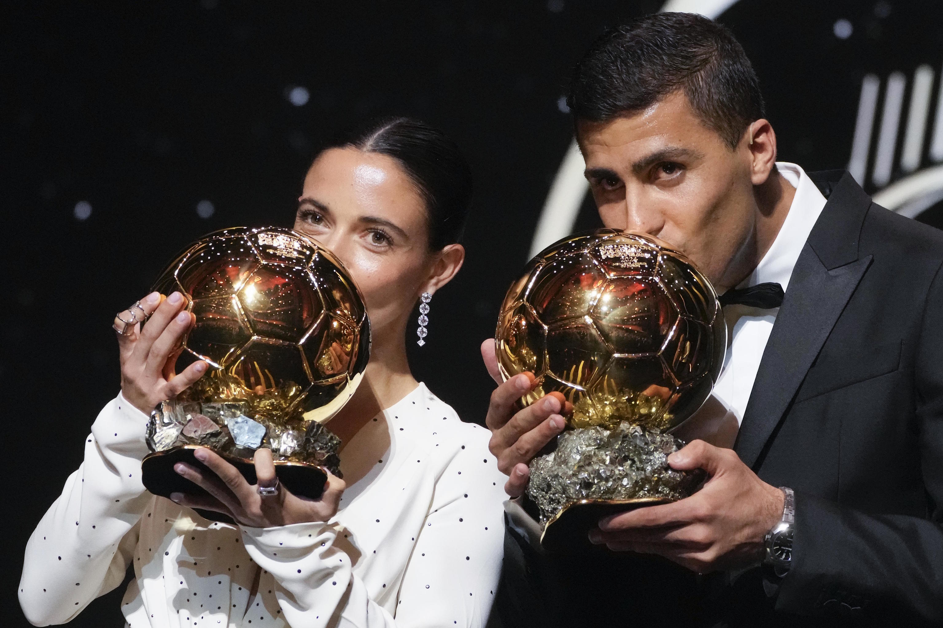 Aitana Bonmati and Rodri kiss their 2024 Ballon d'Or trophies.