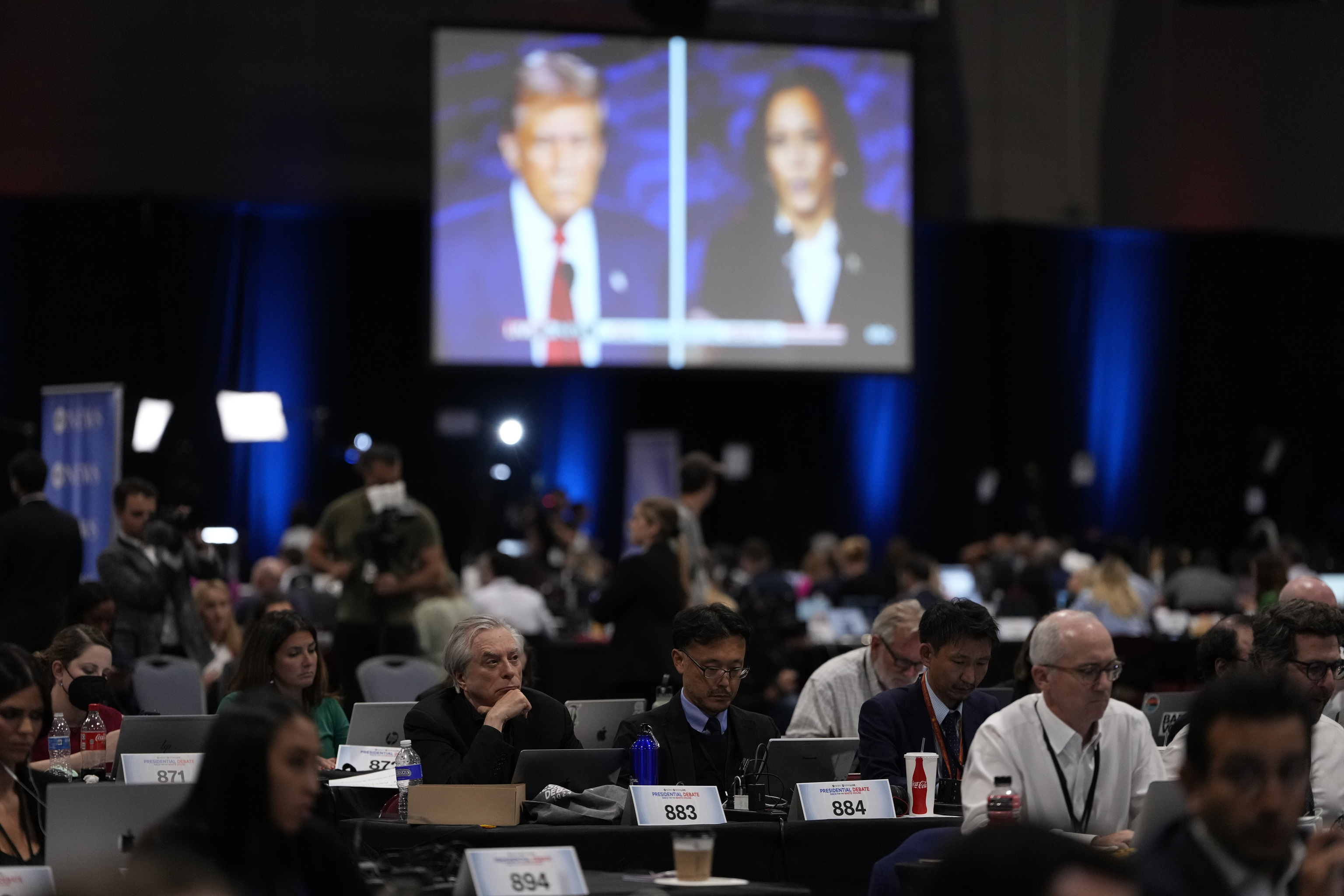 Members of the press work in the spin room during a presidential debate between Republican presidential nominee former President Donald Trump, on screen at left, and Democratic presidential nominee Vice President Kamala Harris