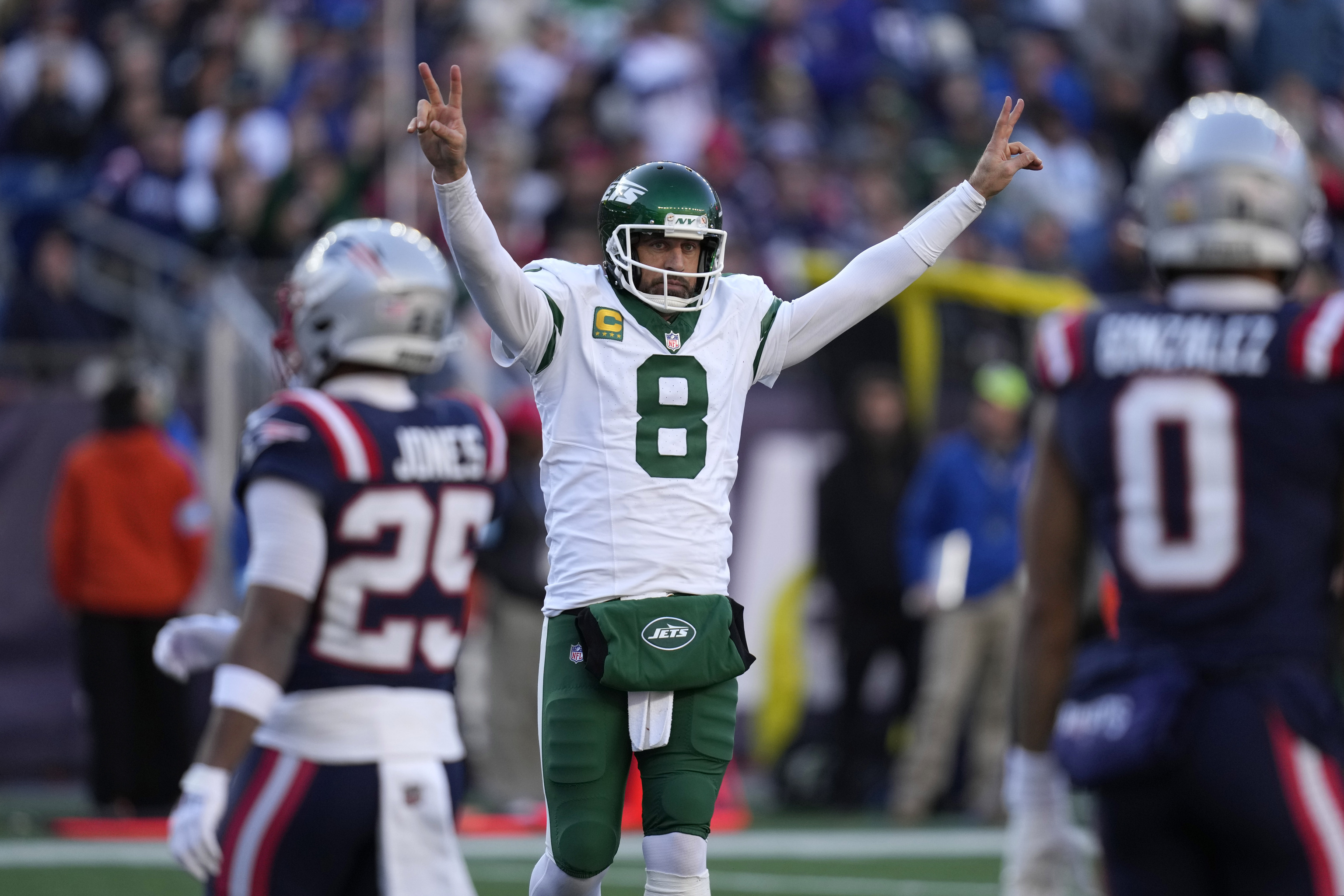 New York Jets quarterback Aaron Rodgers (8) celebrates in front of New England Patriots cornerback Marcus Jones.