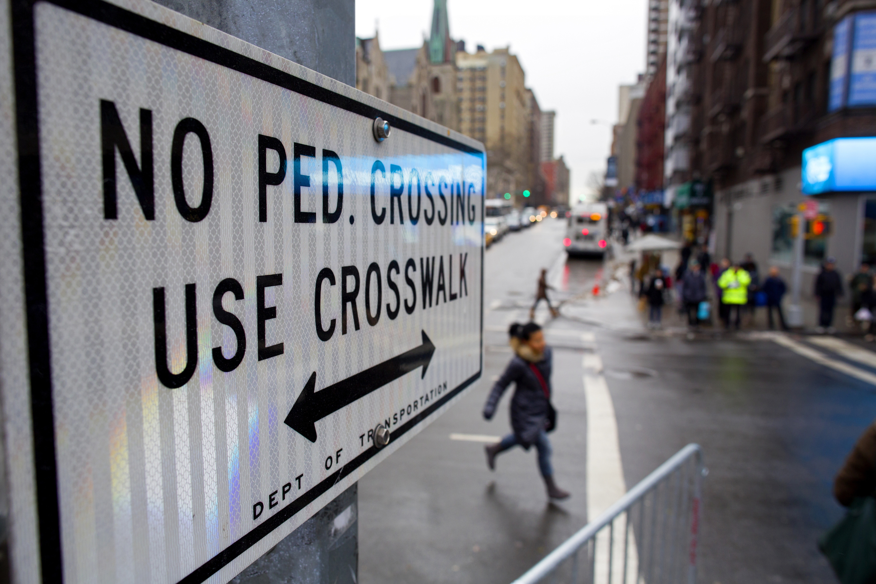 After crossing outside a crosswalk, a pedestrian, center, runs towards a crosswalk at the busy intersection of W. 96th Street and Broadway in the Upper West Side of New York