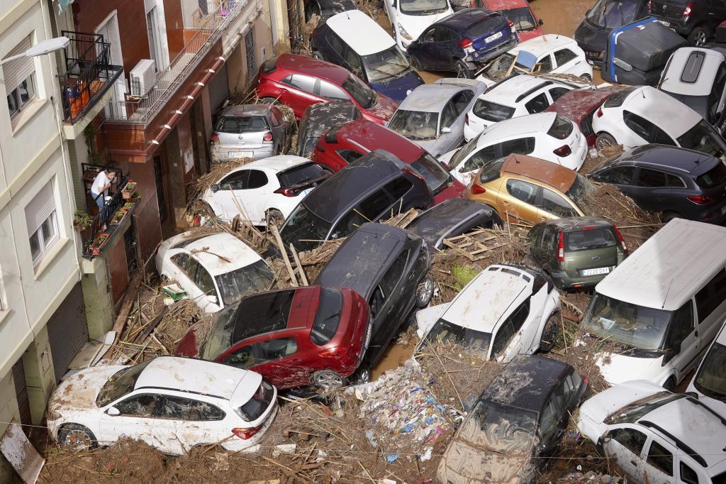 Residents look at cars piled up after being swept away by floods in Valencia