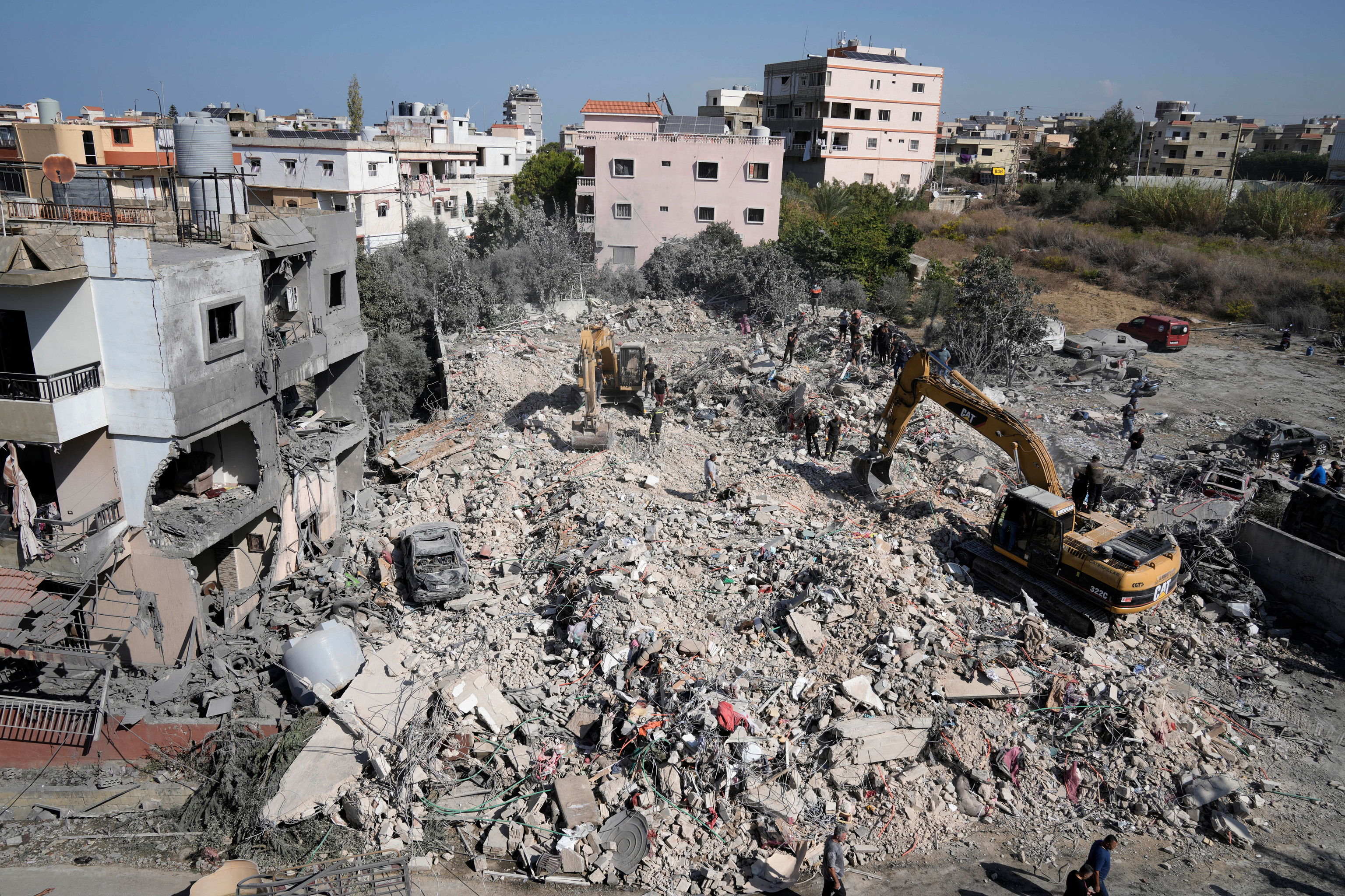 Rescue workers use excavators to remove the rubble of a destroyed building in Lebanon.