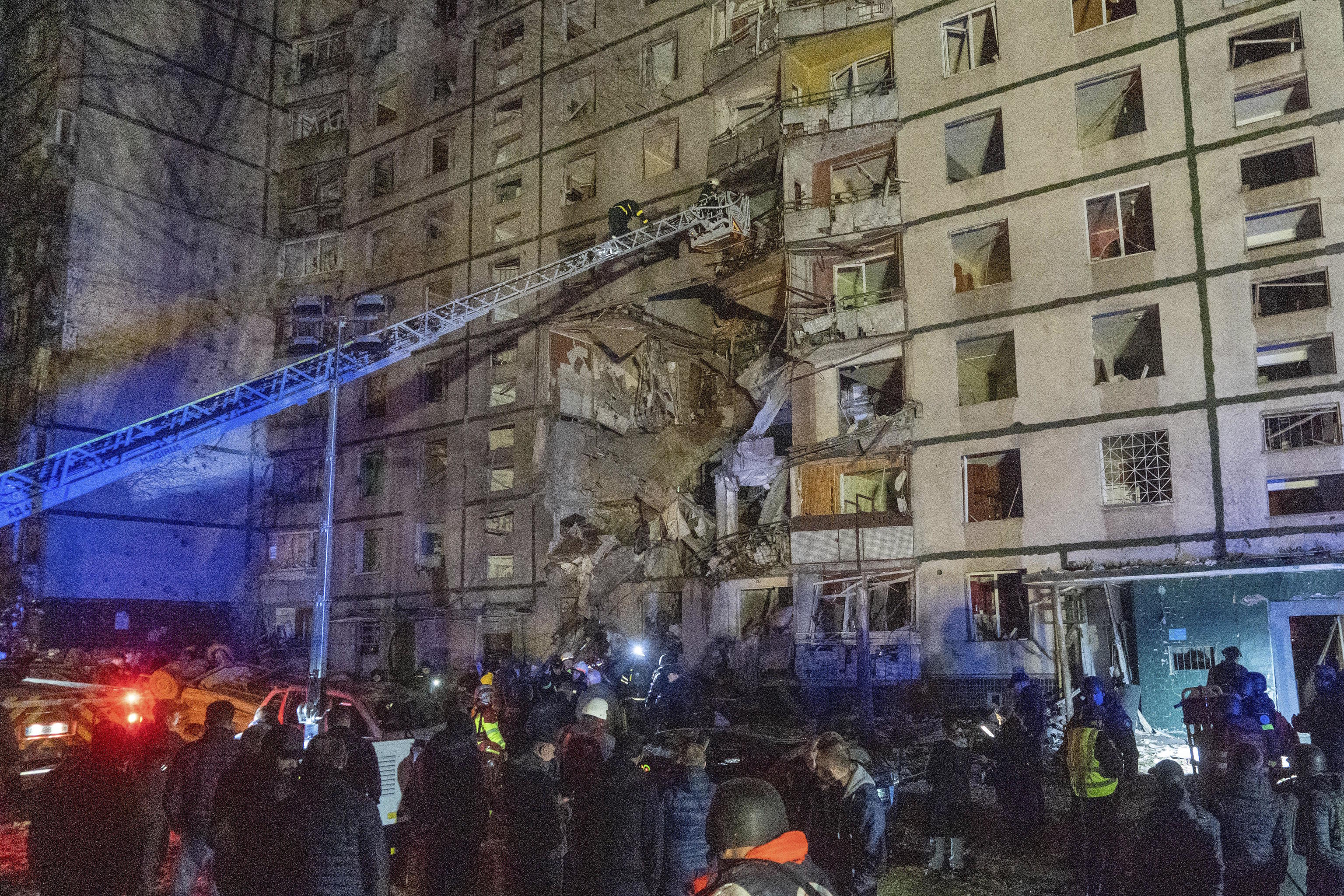 Rescuers help people after a building was hit by Russian attack in Kharkiv.