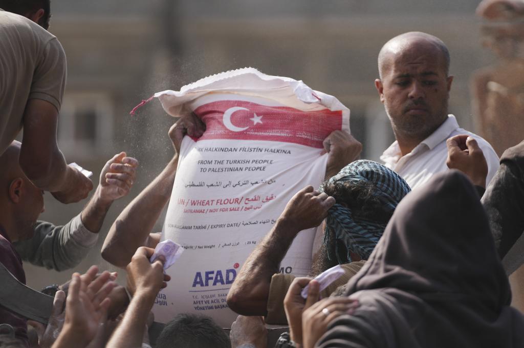 Palestinians gather to receive bags of flour distributed by UNRWA, the U.N. agency helping Palestinian refugees