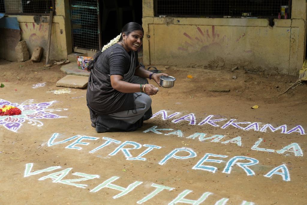 Local politician Arulmozhi Sudhakar reacts as she prepares a Kolam, a traditional art work using colored powder, that reads "Greeting America, our wishes for Kamala Harris' victory"