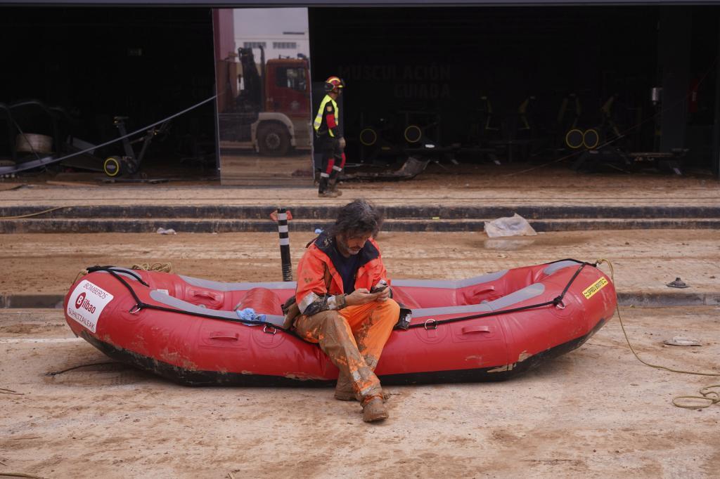 A firefighter sits on a dingy waiting to enter a flooded underground car park in the MN4 shopping centre