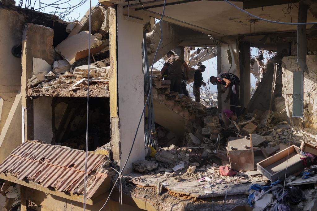 Civil defense workers inspect the rubble of a destroyed building hit in an Israeli airstrike