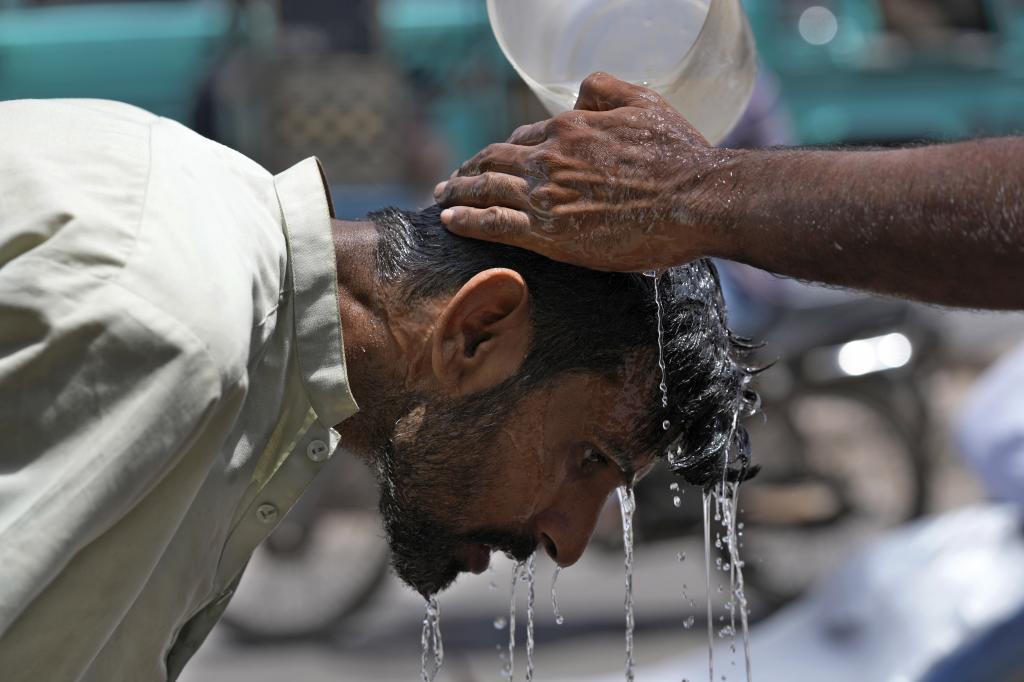 A volunteer pours water to cool a man off during a hot day in Karachi, Pakistan