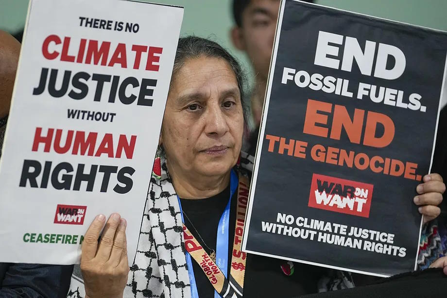 An activist holding signs demanding climate justice.