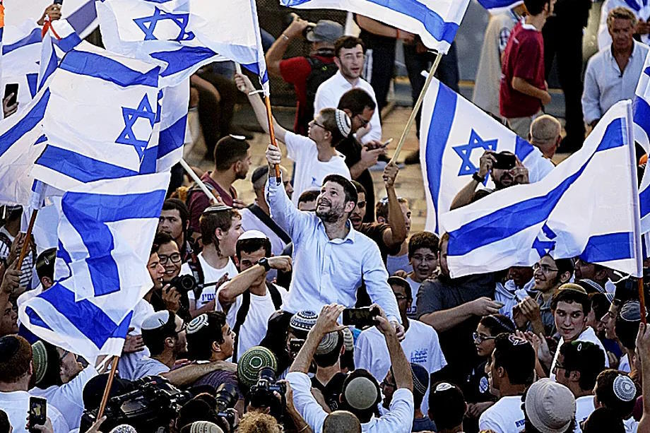 Bezalel Smotrich, the current Israeli Minister of Finance, waving a flag of his country at an ultra-Orthodox celebration three years ago.