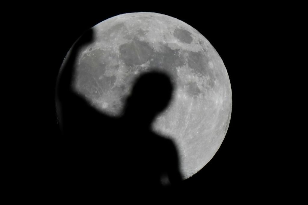 The moon rises behind a spire of the Duomo gothic cathedral, in Milan,