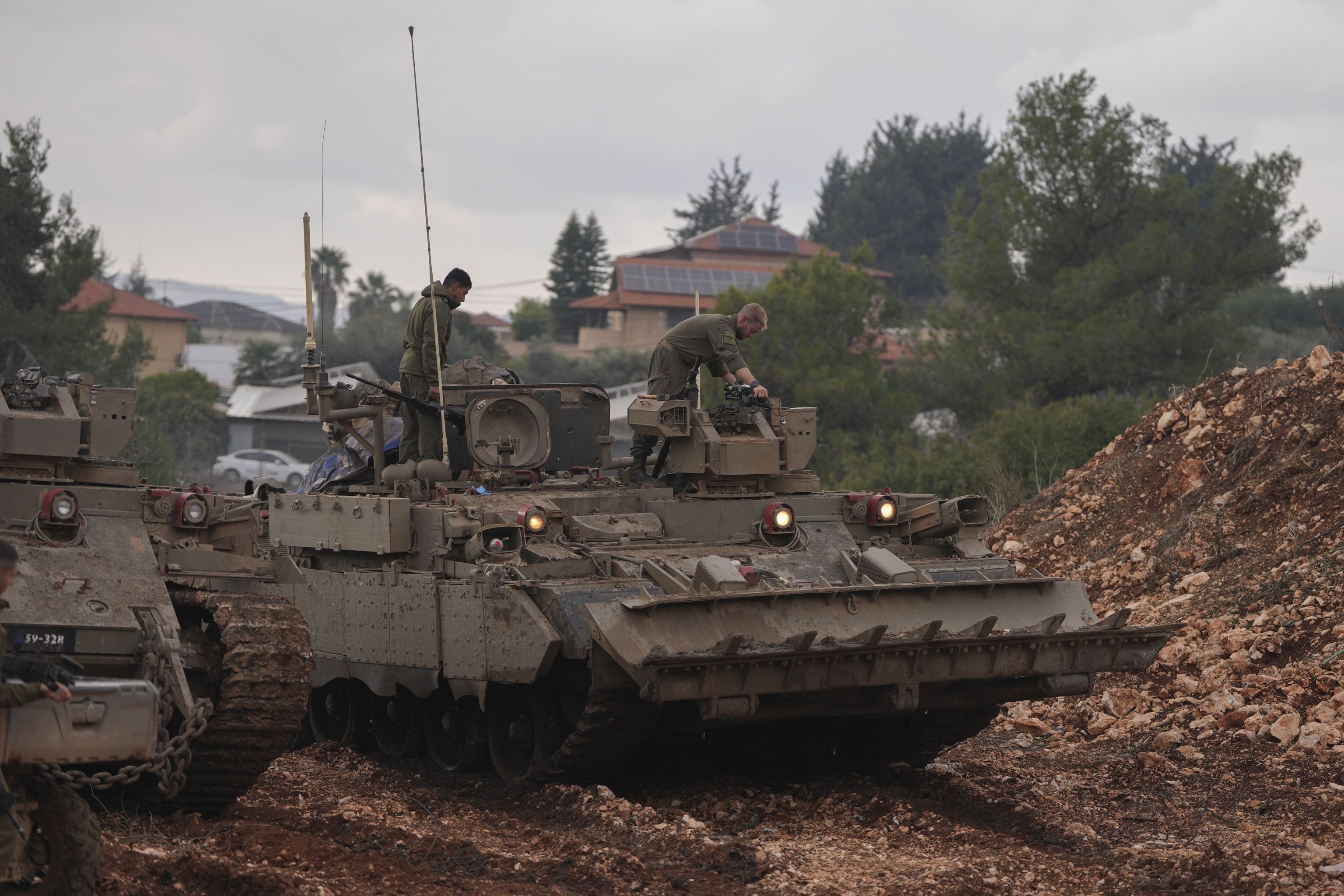 Israeli soldiers stand atop army armoured vehicles outside the agricultural settlement of Avivim.