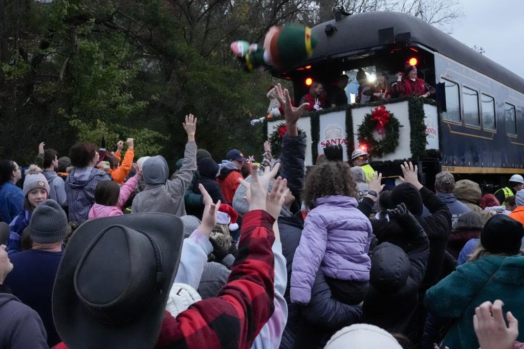 People reach for toys tossed from the CSX Santa Train