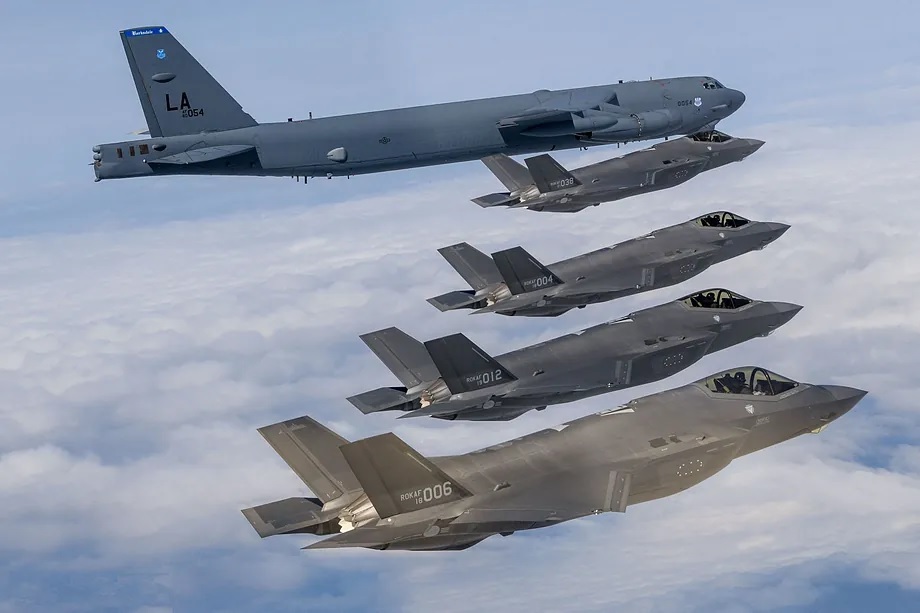 Several South Korean Air Force fighter jets flying alongside a U.S. bomber.