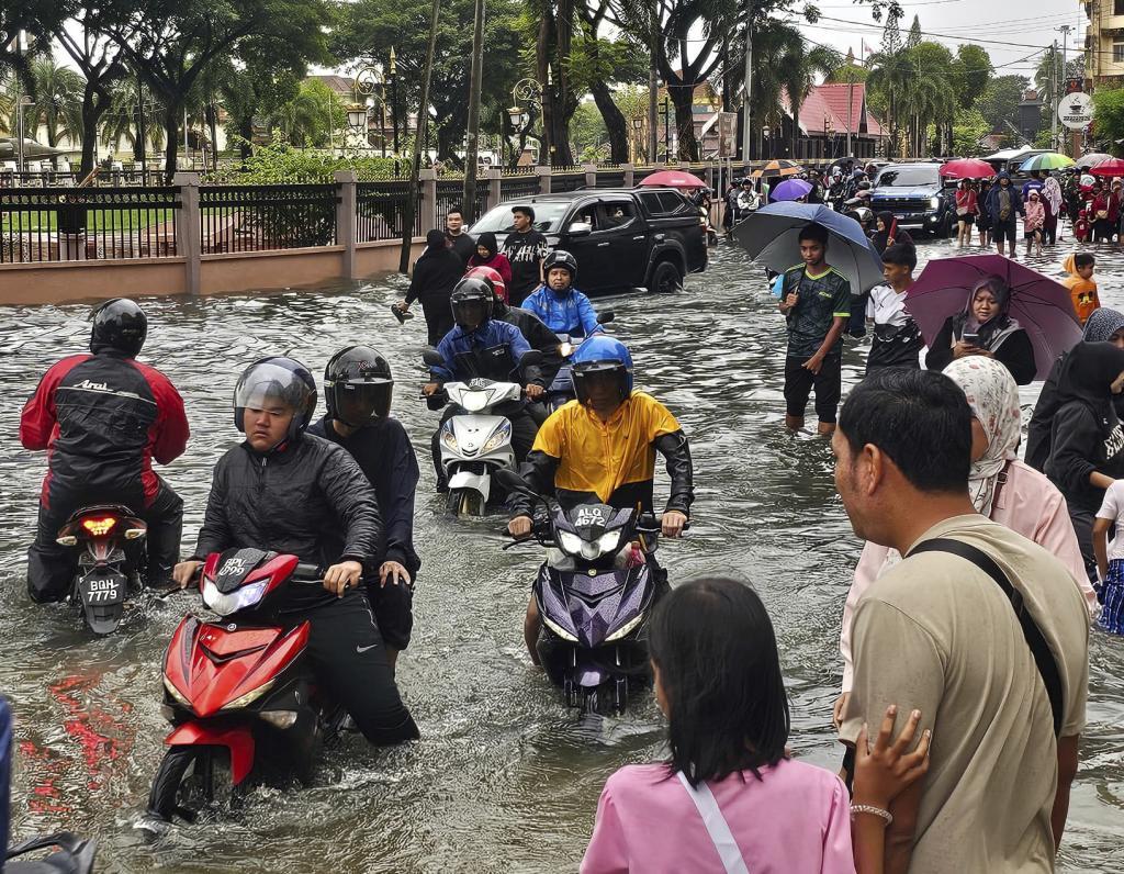 Motorist cross a flooded street after heavy monsoon rains in downtown Kota Bharu