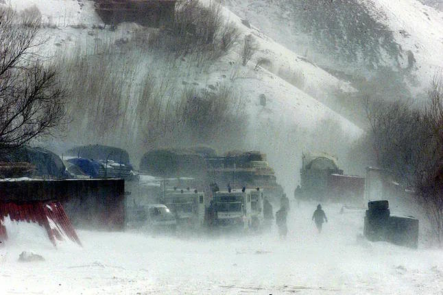 Several people under heavy snowfall in a mountainous region of Afghanistan.