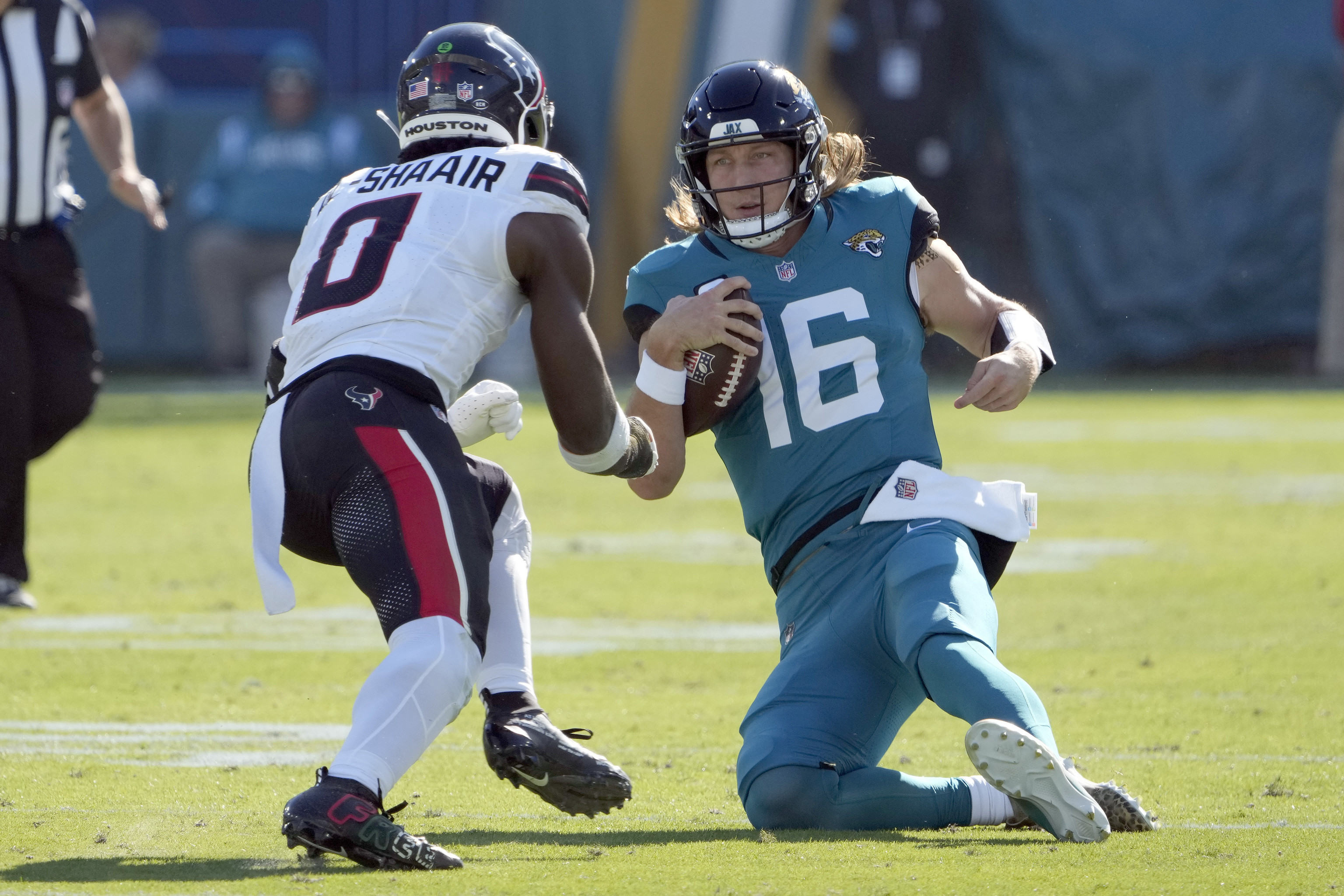 Jacksonville Jaguars quarterback Trevor Lawrence (16) slides in front of Houston Texans linebacker Azeez Al-Shaair (0).