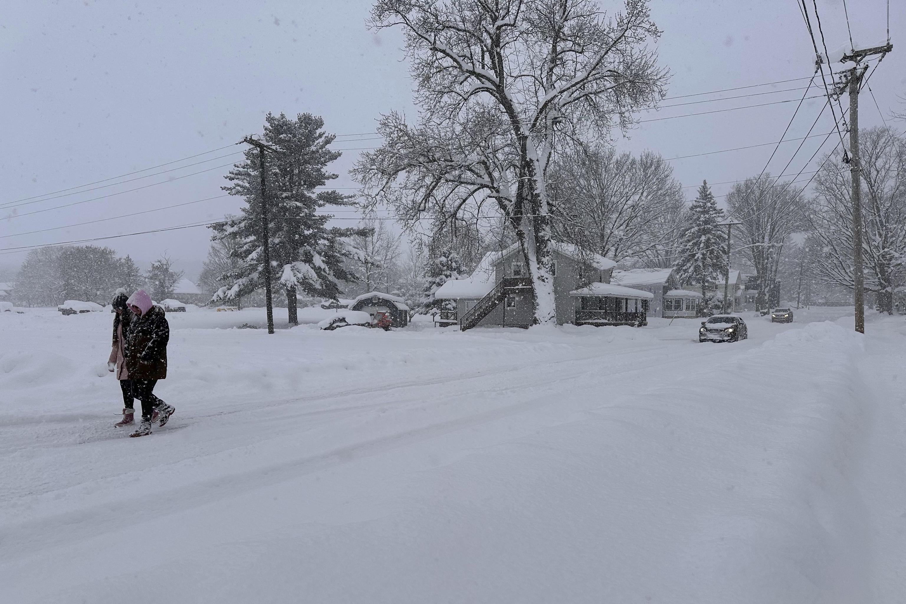 People walk in lake-effect snow in Lowville, N.Y.