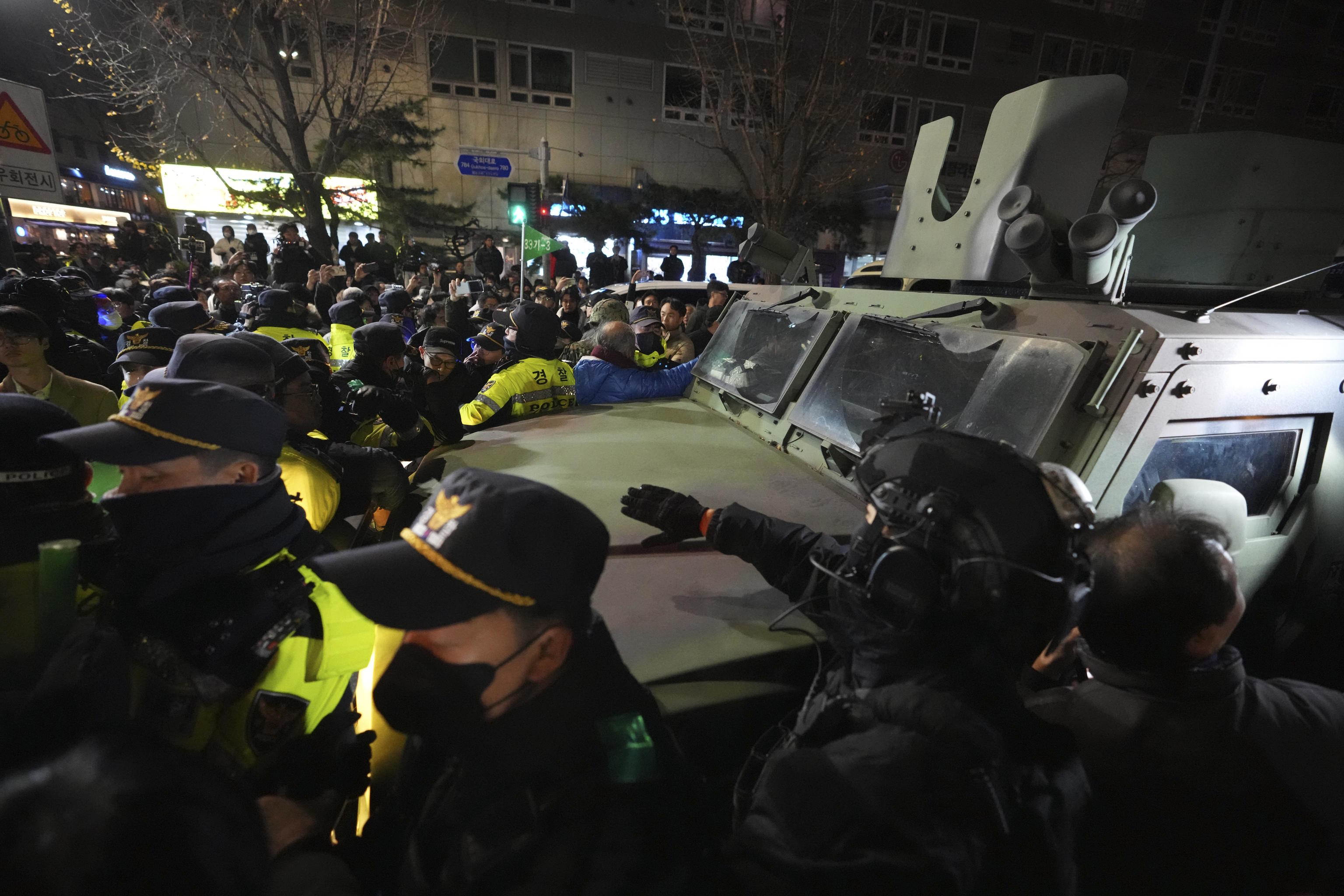 Military vehicle is escorted by police officers.