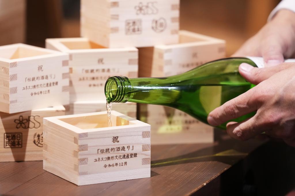 A person prepares for a display as he pours Japanese sake