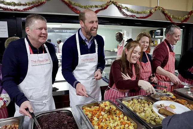 Prince William serves food at The Passage center.