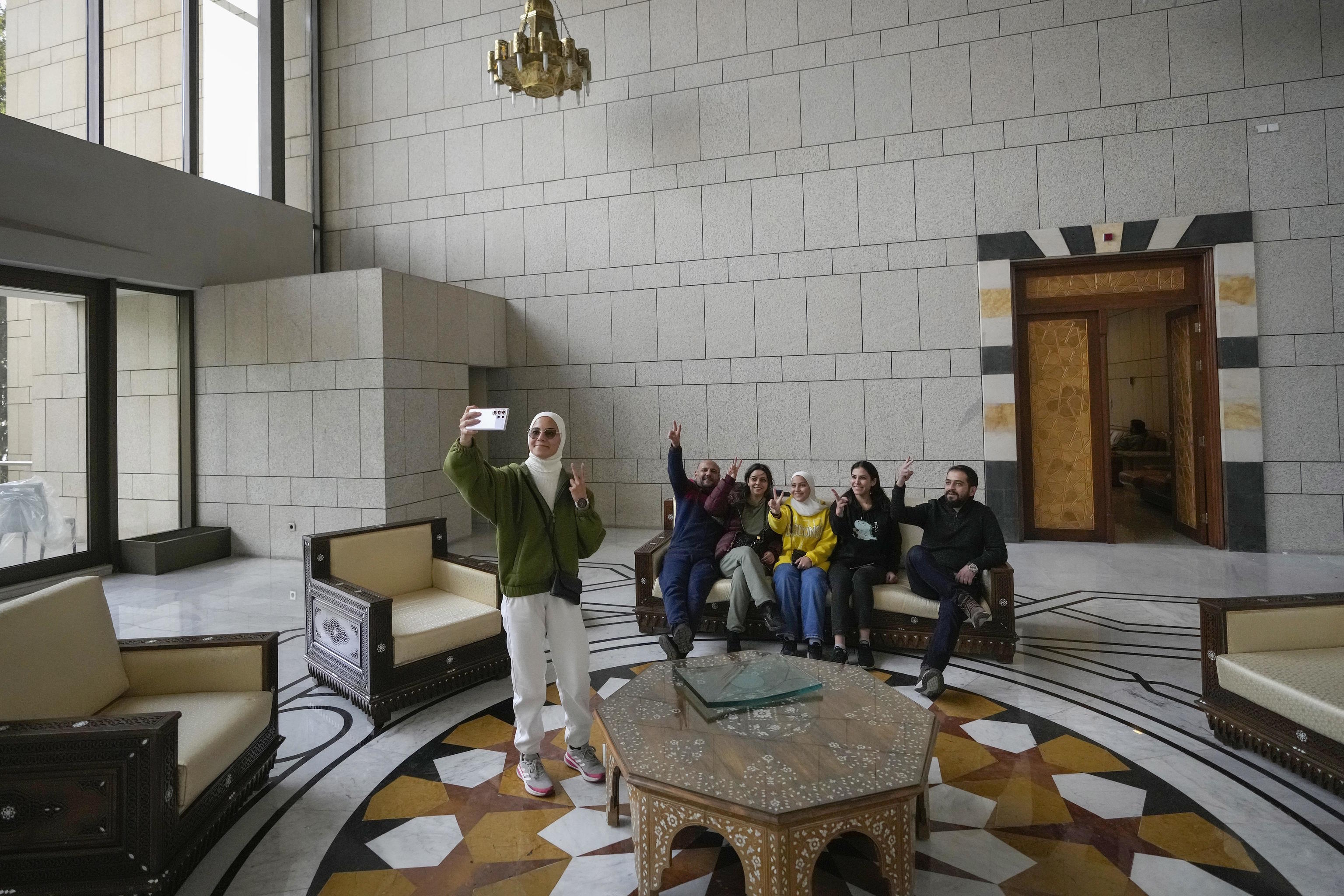 A group of people take a photo in a hall of Bashar Assad's presidential palace.