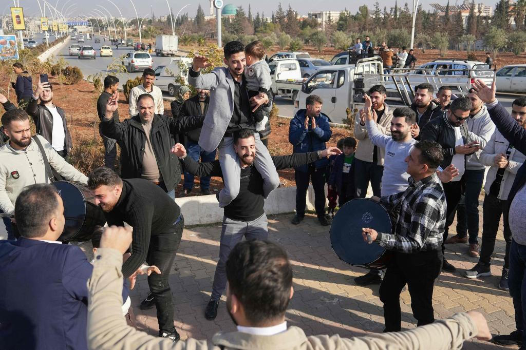 Men just released from prison dance at the entrance of Aleppo city.