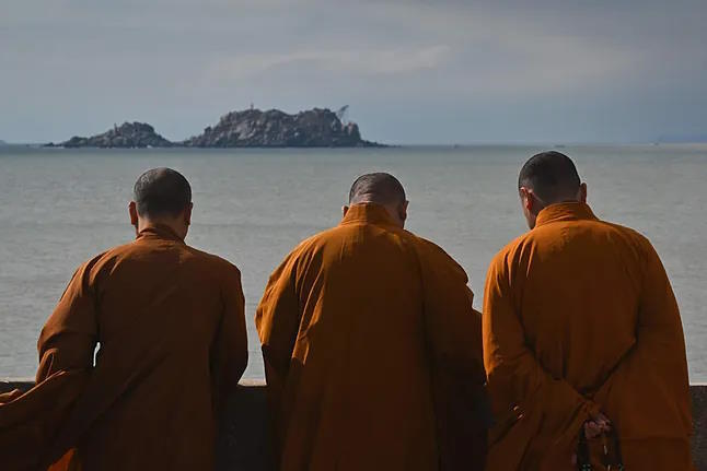 Buddhist monks gaze at the sea from a temple on Pingtan Island.