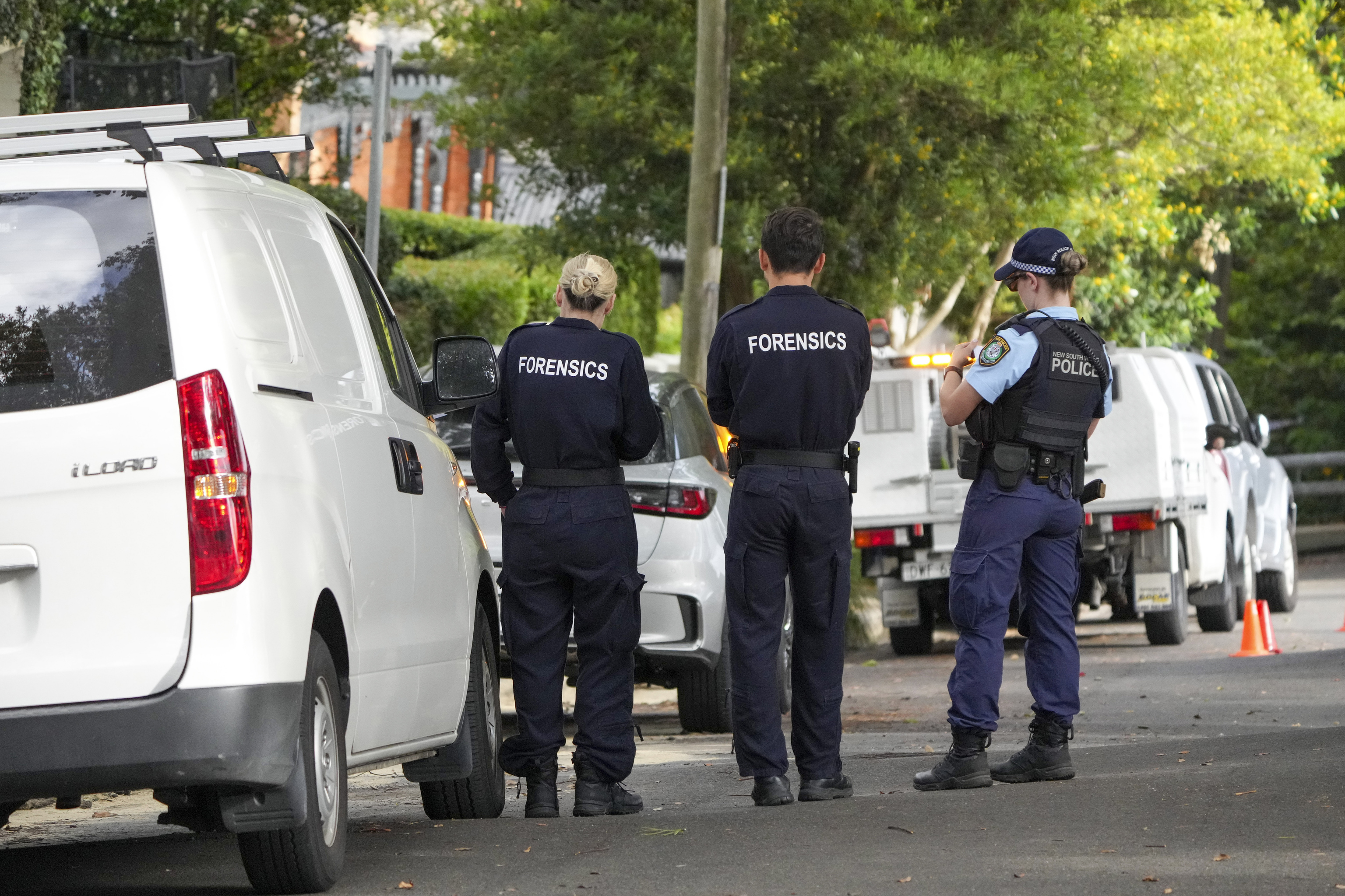 Police stand near houses.