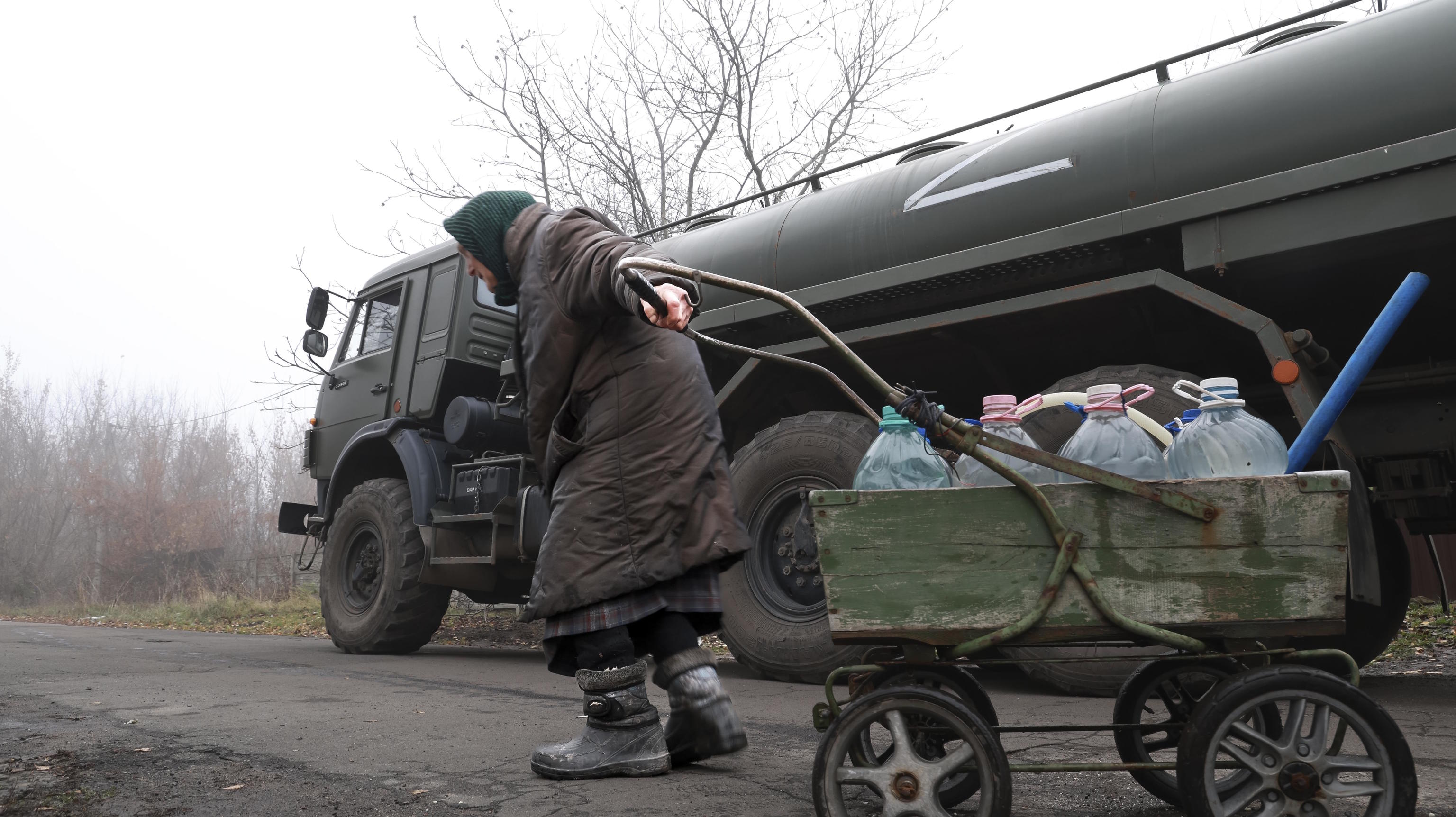 An elderly civilian pulls a cart with bottles of pure water outside Donetsk.