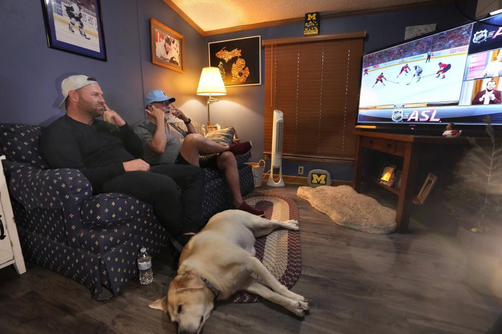 Bob Madden, center, and his son Jonathan, left, watch the Stanley Cup hockey final from a couch