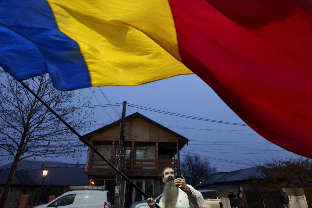 A man waves a Romanian flag outside the closed polling station where Calin Georgescu