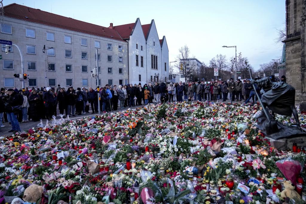 People lay flowers and lit candles in front of the Johannis church close to the Christmas market