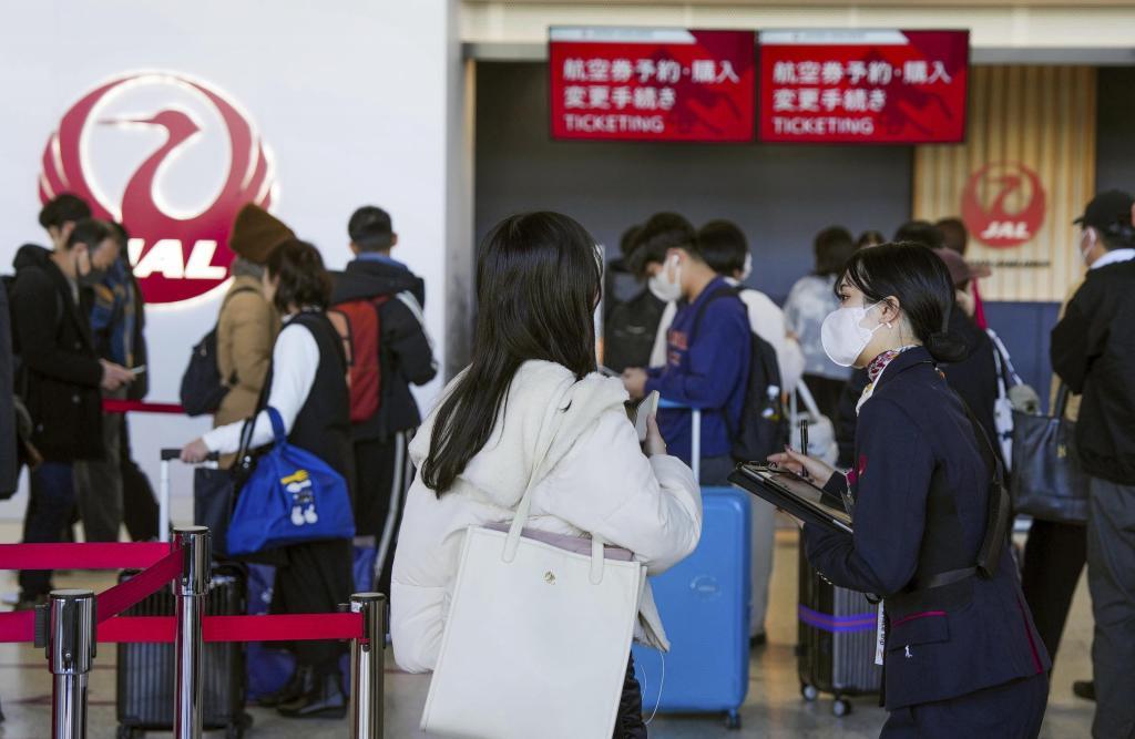 A staff member of Japan Airlines helps customers at Osaka International Airport