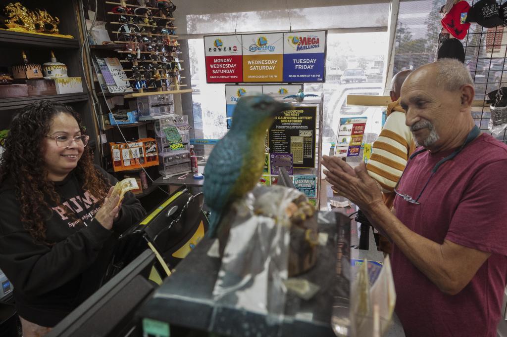 Painter Ivan Minera rubs his hands as he purchases California lottery tickets at Bluebird Liquor