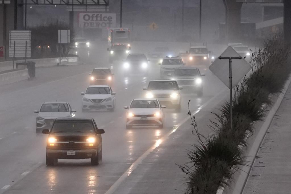 Several vehicles make their way on a rain-soaked freeway in Dallas