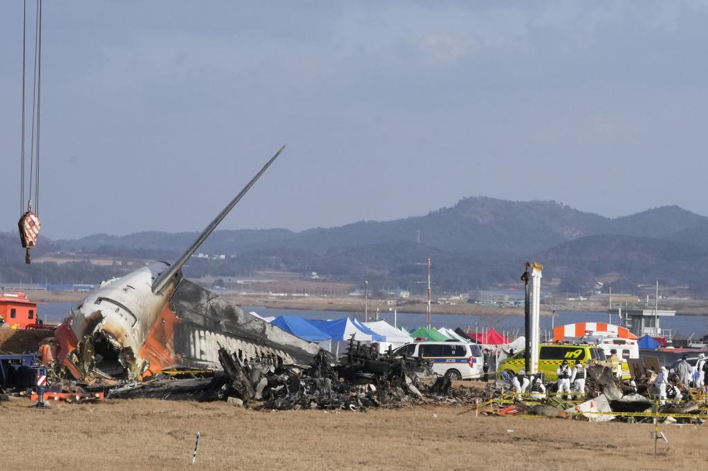 Rescue team members work at the site of a plane fire at Muan International Airport in Muan