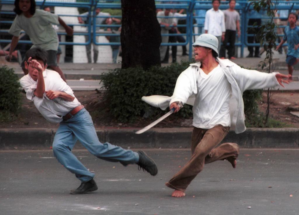 A young Indonesian man assaults otor with a machete during a street clash between rival gangs in Jakarta.