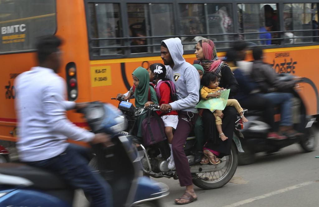 An Indian motorist ferrying four children and a woman rides in the wrong direction during morning rush hour in Bangalore