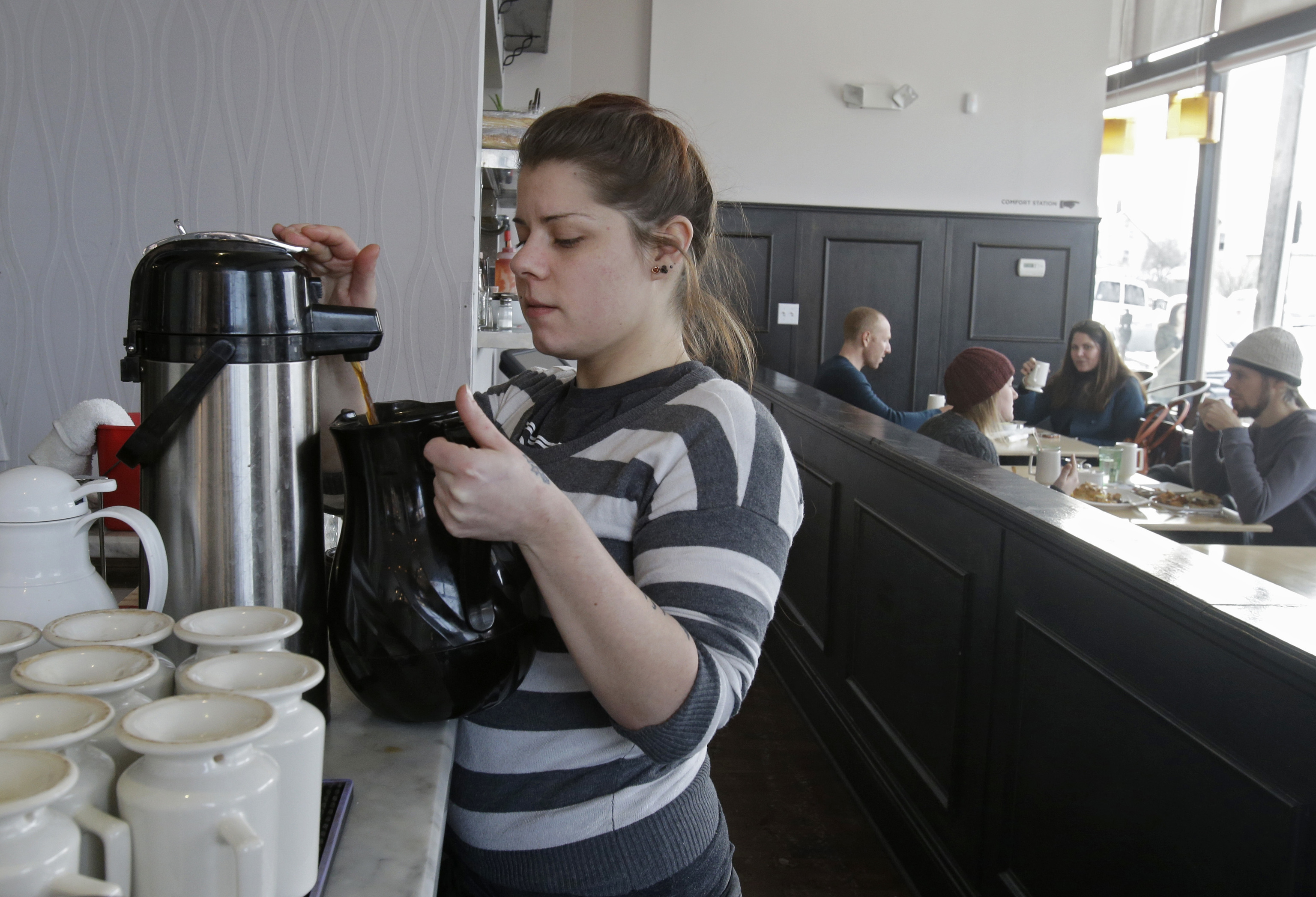 A server fills a carafe with hot coffee.