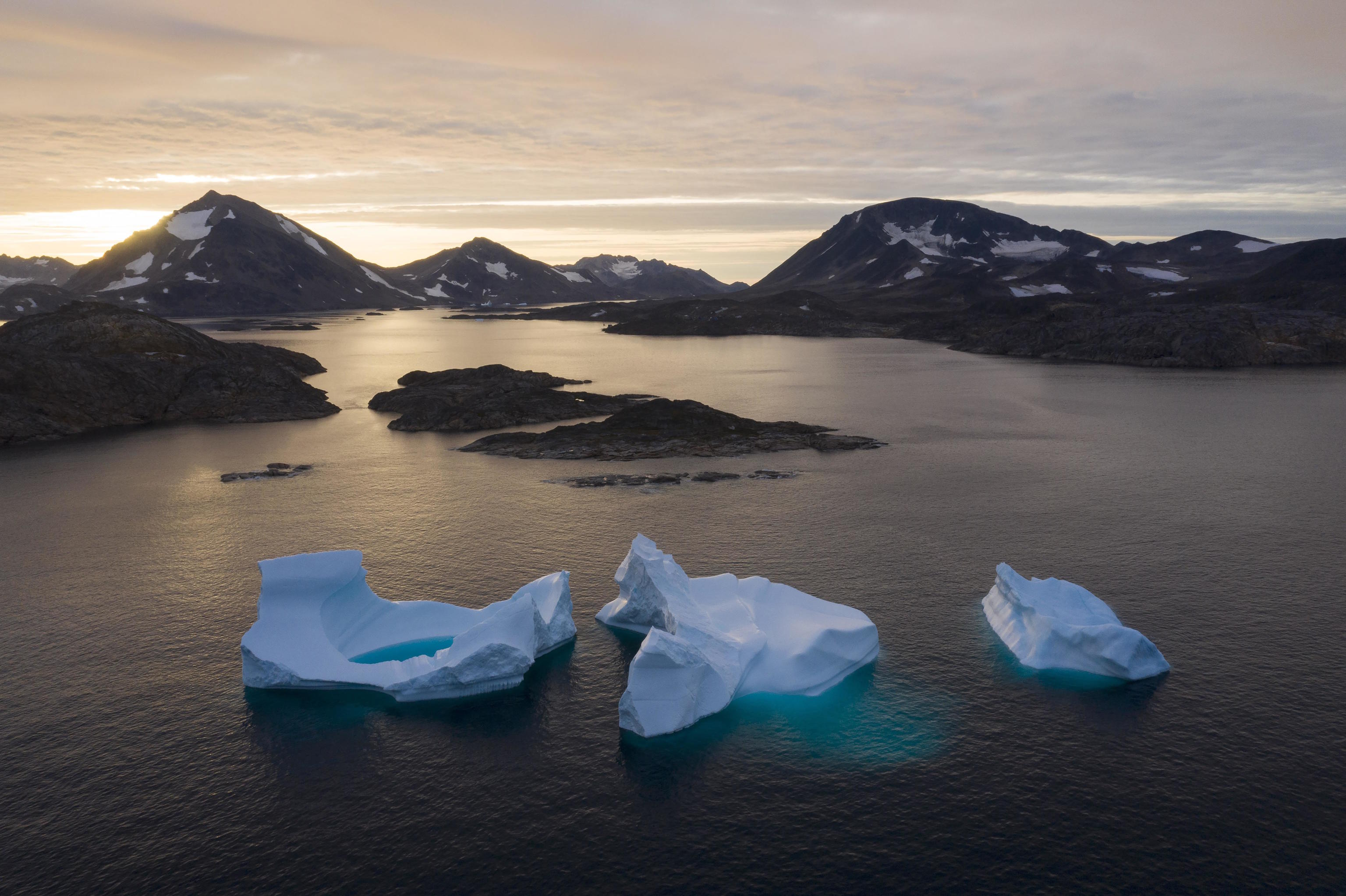 Large icebergs float away as the sun rises near Kulusuk, Greenland.