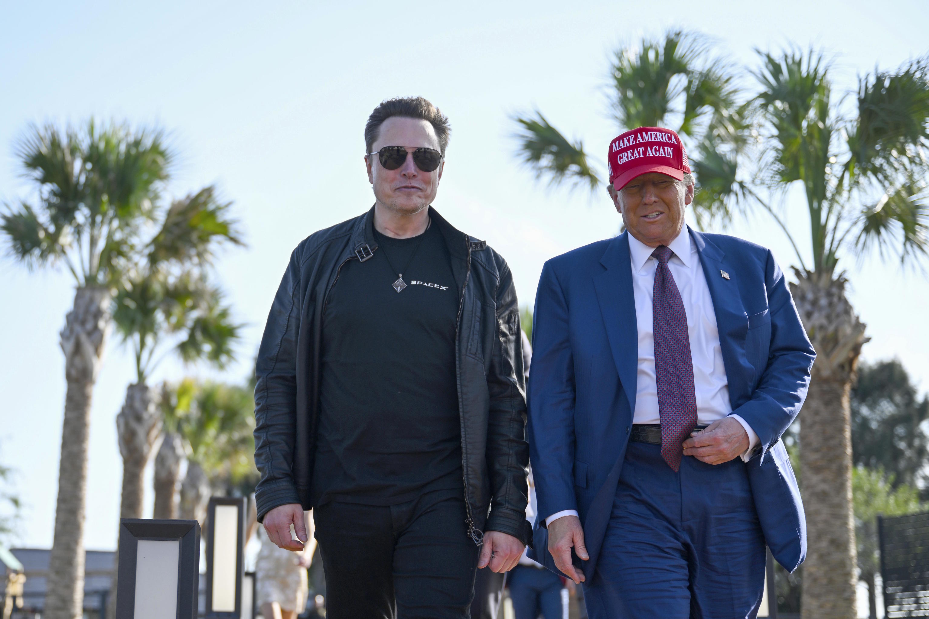 Donald Trump walks alongside Elon Musk.