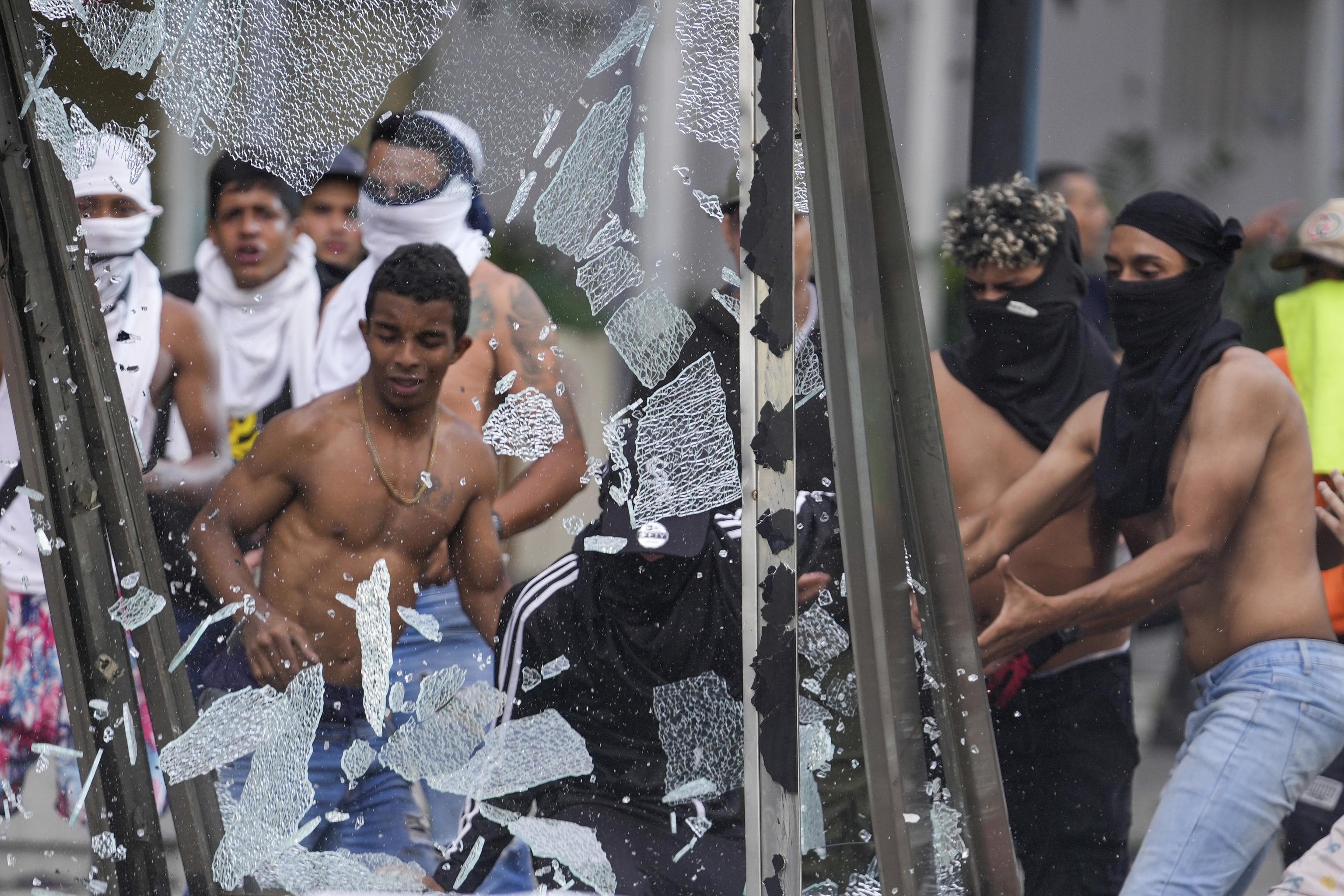 Protesters smash an advertising board during demonstrations against Maduro.