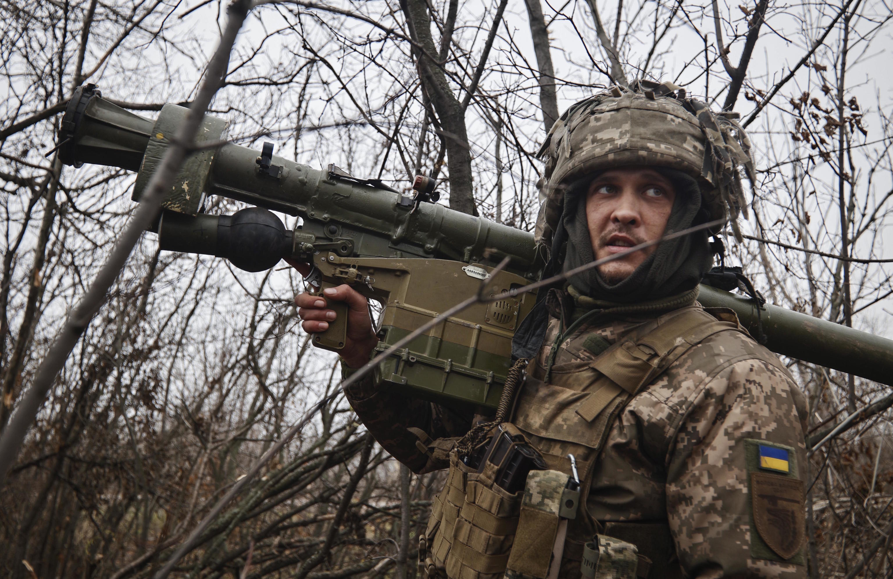 An Ukrainian soldier stands holding an anti-aircraft rocket launcher.