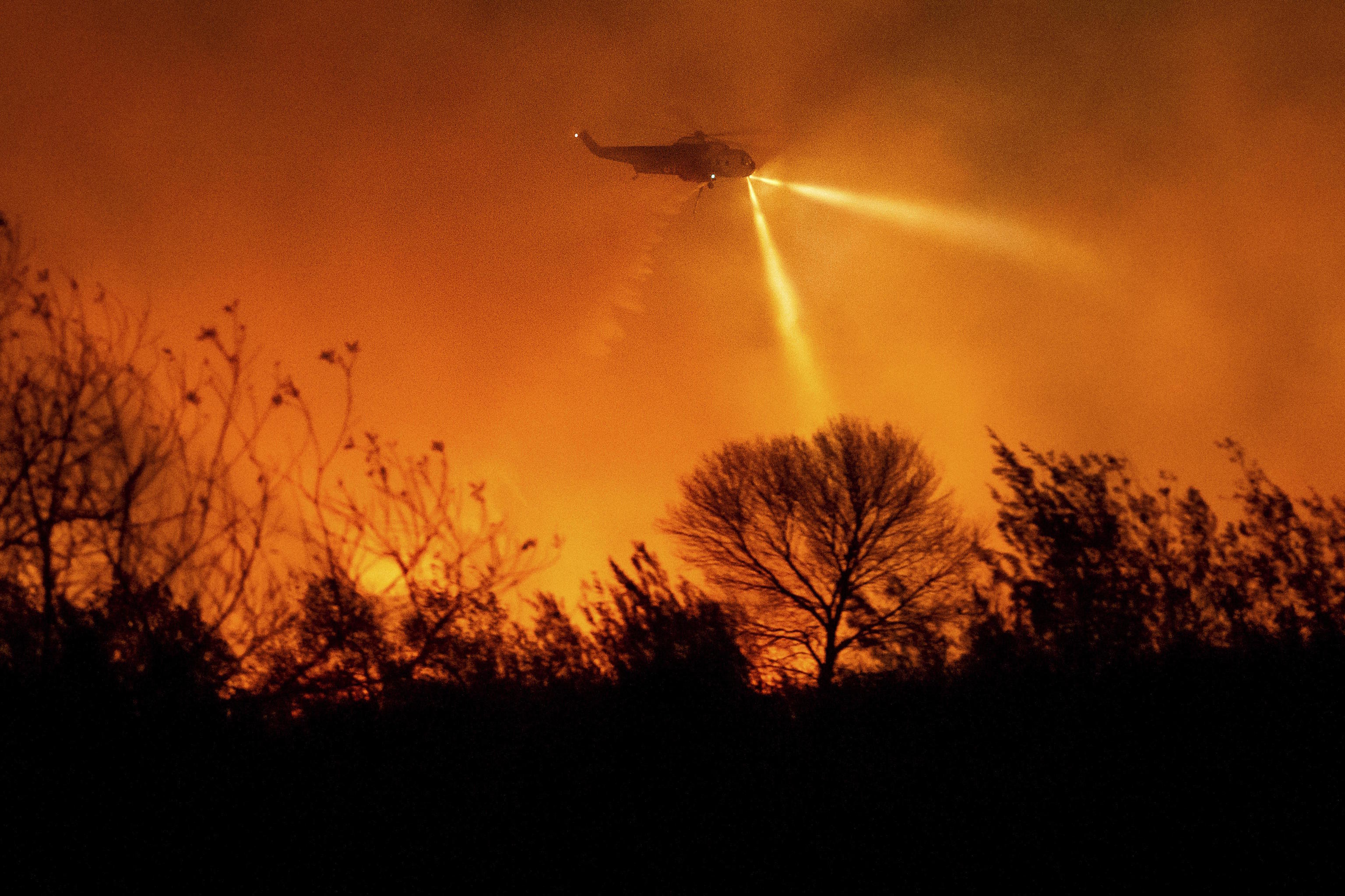 A helicopter drops water while fighting the Auto Fire in Ventura County, Calif.,