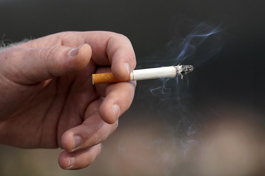 A man holds a lit cigarette while smoking in San Francisco