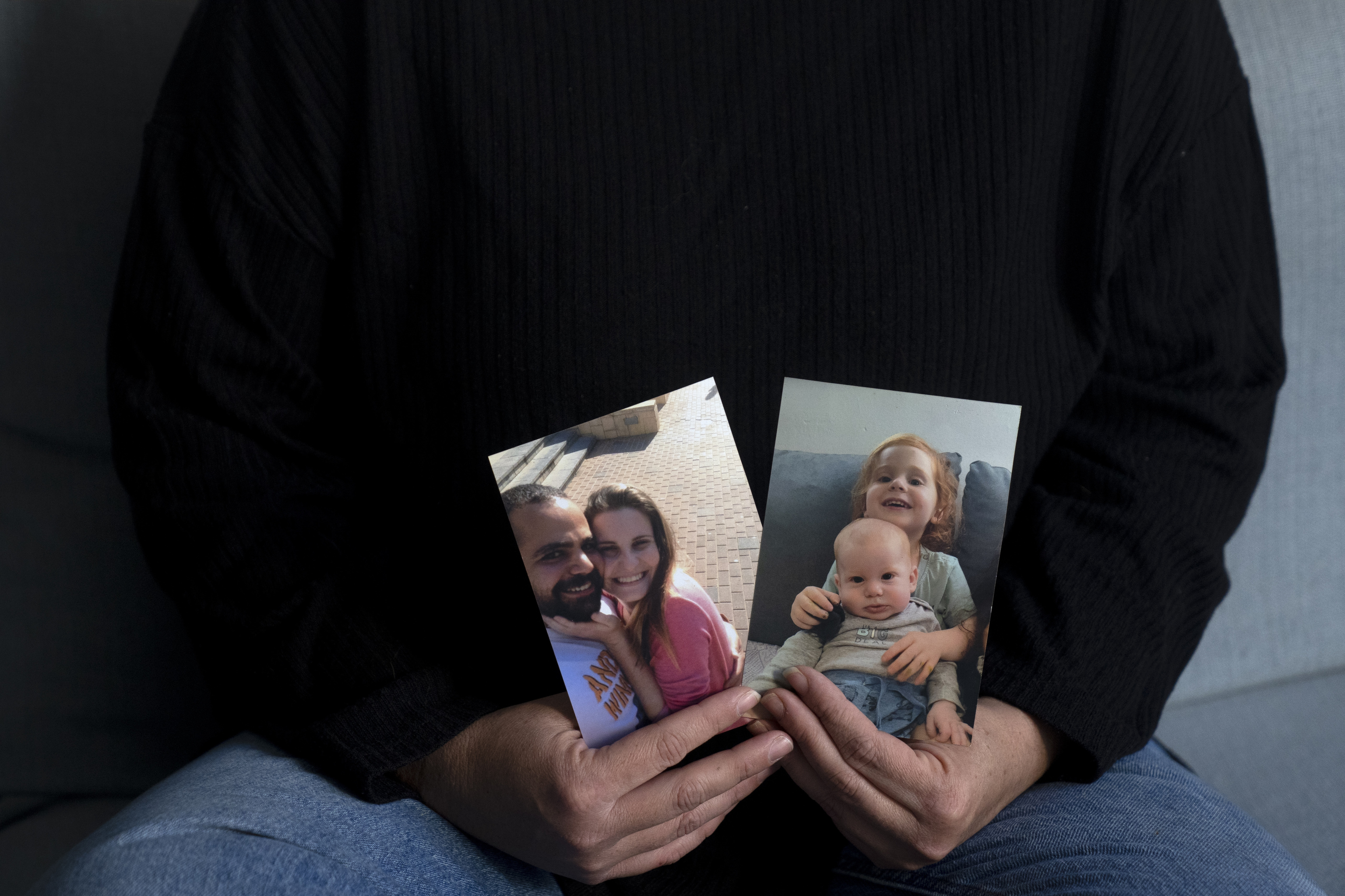 Yifat Zailer shows photos of her cousin, Shiri Bibas, center, her husband Yarden, left, and their sons Ariel, top right, and Kfir, who were taken hostage by Hamas militants.