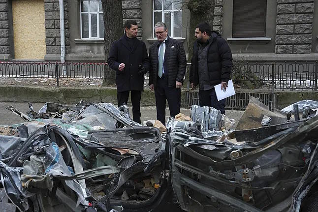 Starmer inspects a damaged vehicle on a road before talks with Zelenski.